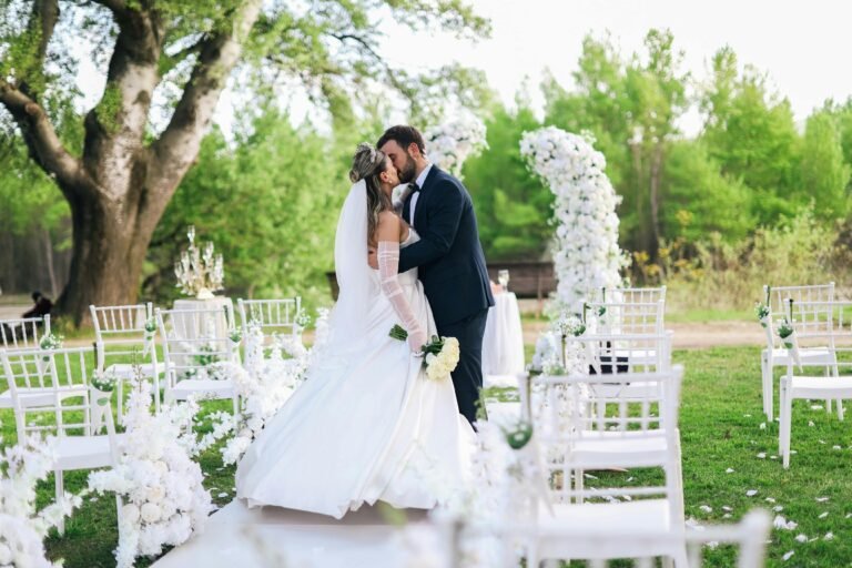 Bride and groom sharing a kiss at their outdoor spring wedding ceremony with elegant decor.