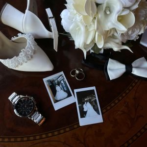 Elegant arrangement of wedding items including shoes, bouquet, and photos on a table.