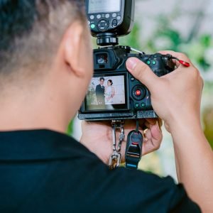 A photographer focuses on capturing a wedding couple using a digital camera during a ceremony.